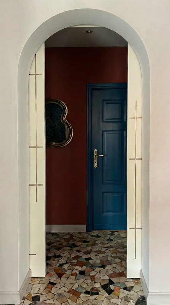 Vista attraverso porta ad arco aperta che mostra il contrasto tra il pavimento in graniglia classico e le pareti colorate moderne.